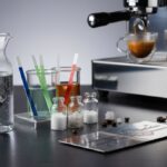 Glass beaker with clear water and mineral concentrates next to a portafilter and espresso puck